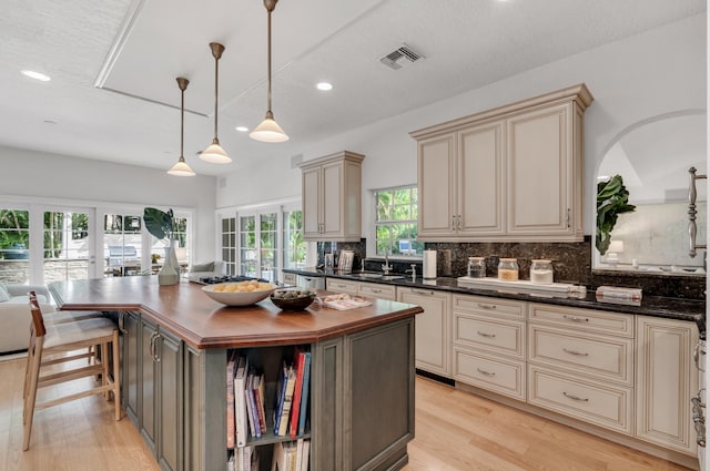 kitchen with wood counters, decorative light fixtures, cream cabinets, and a kitchen island