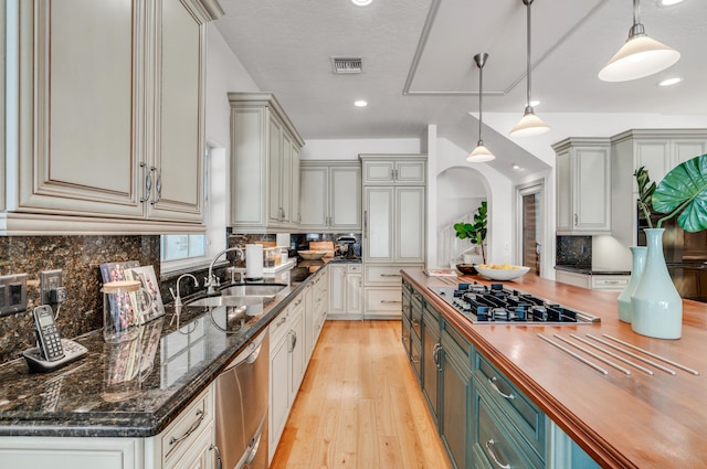 kitchen with butcher block countertops, dishwasher, sink, hanging light fixtures, and gas stovetop