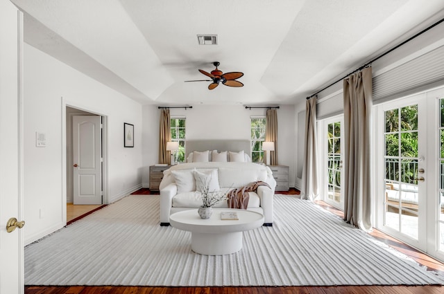 bedroom with ceiling fan, a tray ceiling, and access to exterior