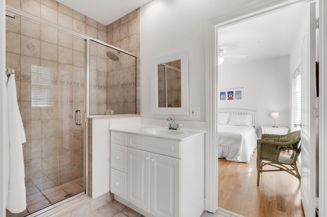 bathroom with a shower with door, vanity, wood-type flooring, and ceiling fan