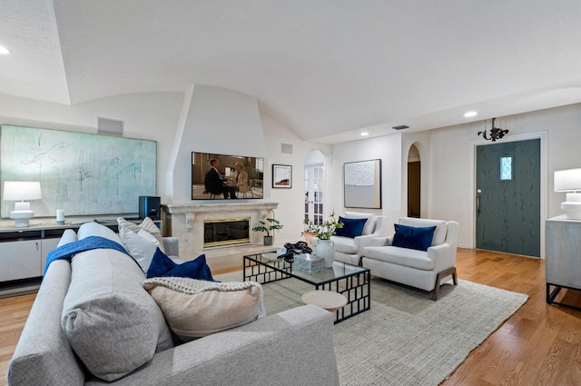 living room featuring vaulted ceiling, a fireplace, and light hardwood / wood-style floors