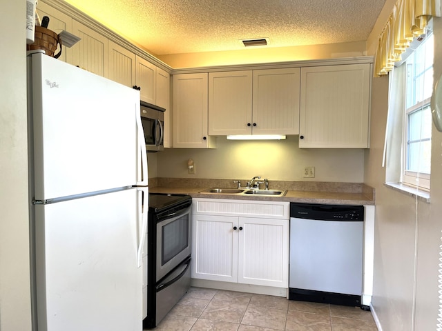 kitchen featuring stainless steel appliances, light tile patterned flooring, sink, and a textured ceiling