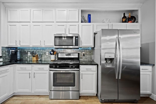 kitchen featuring appliances with stainless steel finishes, dark stone counters, and white cabinets