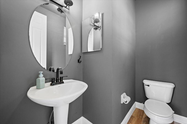 bathroom with wood-type flooring, toilet, and sink