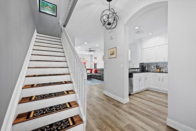 staircase featuring ceiling fan, wood-type flooring, and sink