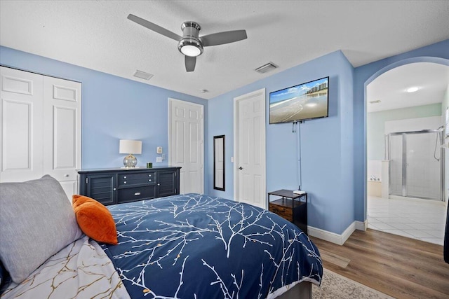 bedroom featuring hardwood / wood-style flooring, ensuite bath, ceiling fan, a textured ceiling, and a closet