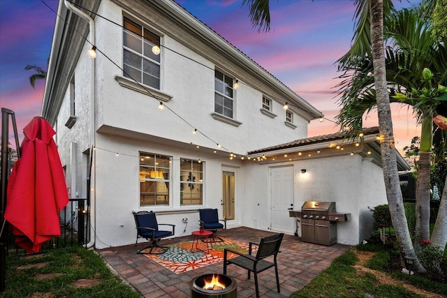 back house at dusk with a patio area and a fire pit