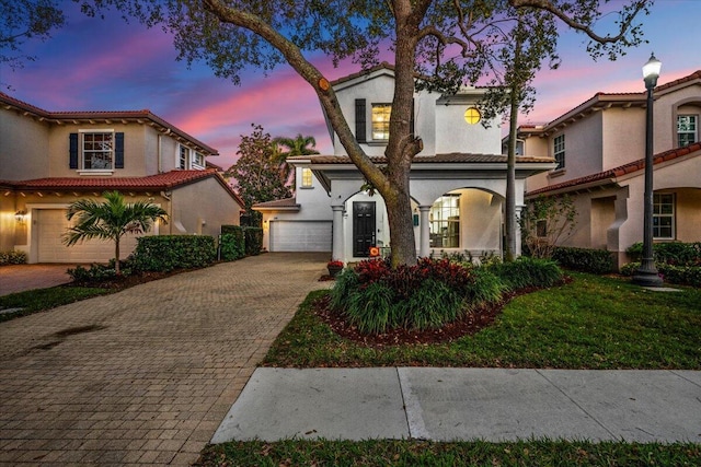 mediterranean / spanish house featuring a garage and a lawn