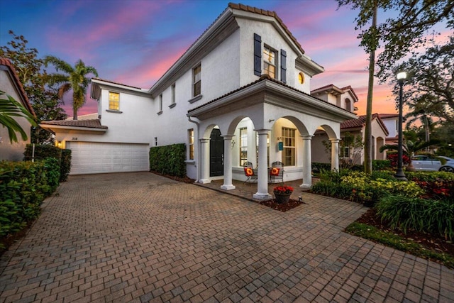 318 September St, Palm Beach Gardens, FL 33410 - mediterranean / spanish-style home with an attached garage, decorative driveway, stucco siding, a tiled roof, and a porch