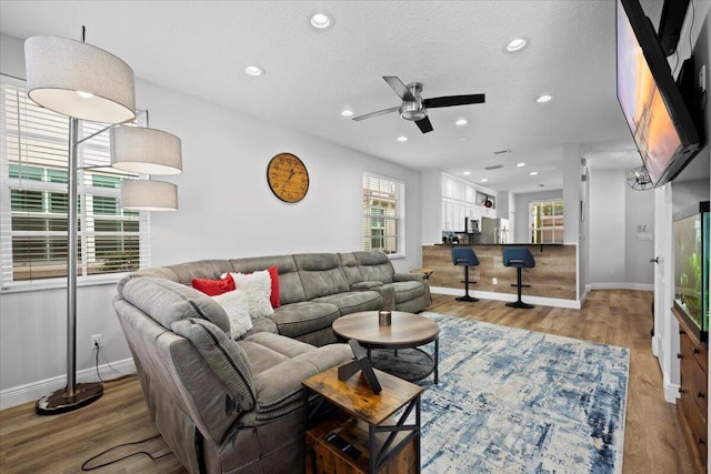 living room featuring ceiling fan, hardwood / wood-style flooring, and a textured ceiling