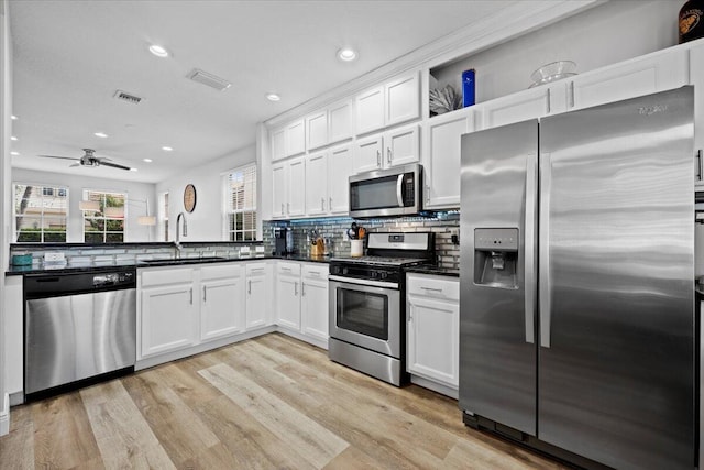 kitchen featuring stainless steel appliances, white cabinetry, sink, and light hardwood / wood-style flooring