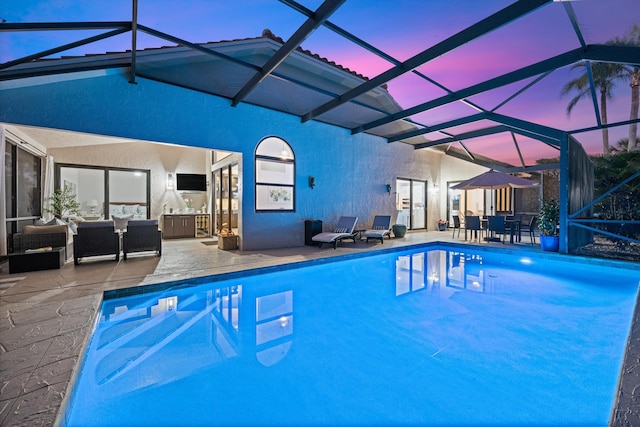 pool at dusk with a patio, a lanai, and an outdoor hangout area