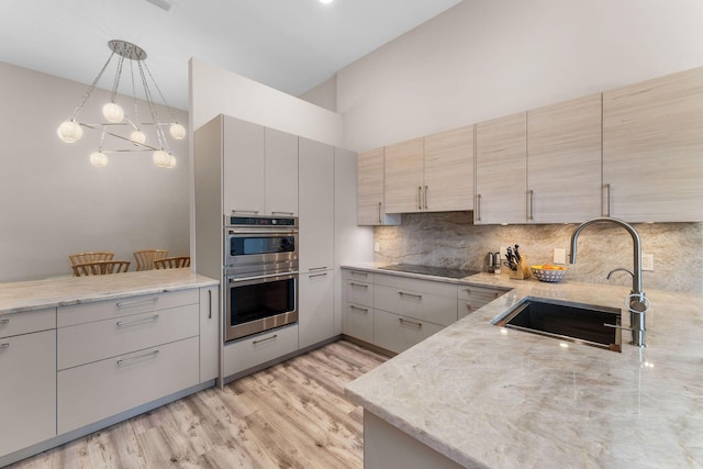 kitchen with stainless steel double oven, hanging light fixtures, black electric stovetop, decorative backsplash, and sink