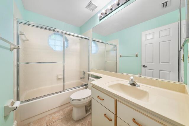 full bathroom with enclosed tub / shower combo, tile patterned floors, toilet, and vanity