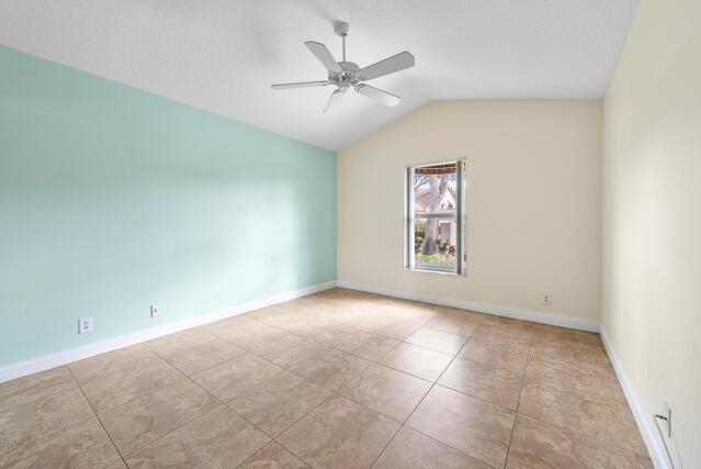 spare room with lofted ceiling, light tile patterned floors, and ceiling fan