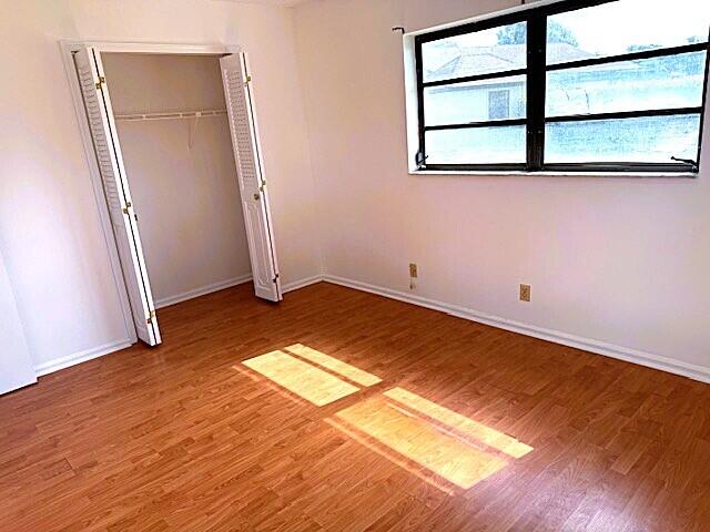 10439 Quailwood Ln Unit B, Boynton Beach, FL 33436 - unfurnished bedroom with wood finished floors, baseboards, and a closet