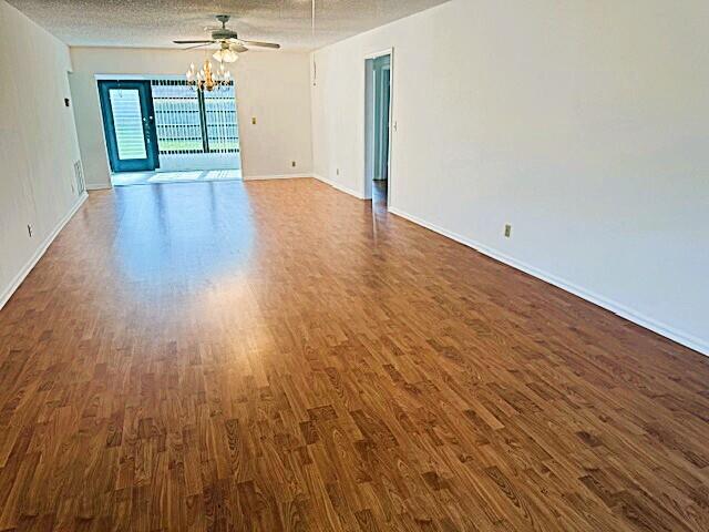 10439 Quailwood Ln Unit B, Boynton Beach, FL 33436 - empty room with dark wood finished floors, a ceiling fan, baseboards, and a textured ceiling
