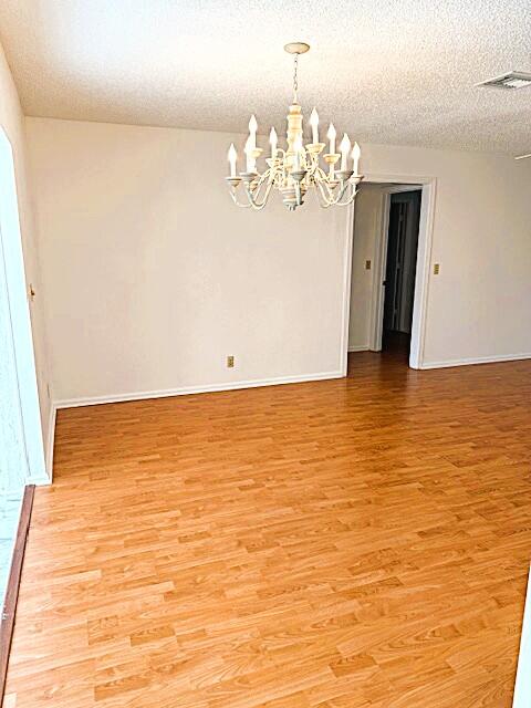 10439 Quailwood Ln Unit B, Boynton Beach, FL 33436 - unfurnished room with a chandelier, light wood-style flooring, baseboards, and a textured ceiling