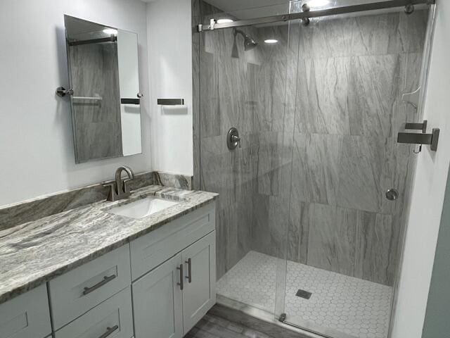 bathroom with a marble finish shower and vanity