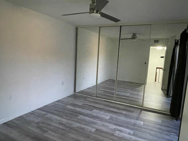 unfurnished bedroom featuring wood finished floors, a closet, and ceiling fan