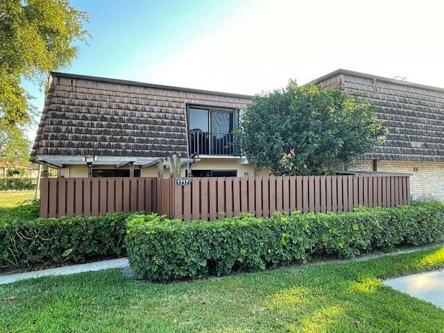 view of property exterior with fence, brick siding, and mansard roof