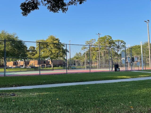 view of sport court featuring fence and a lawn