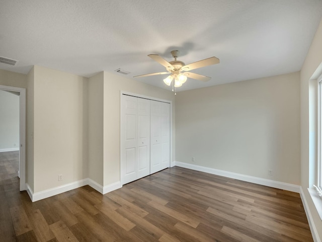 unfurnished bedroom with a closet, a textured ceiling, dark hardwood / wood-style floors, and ceiling fan