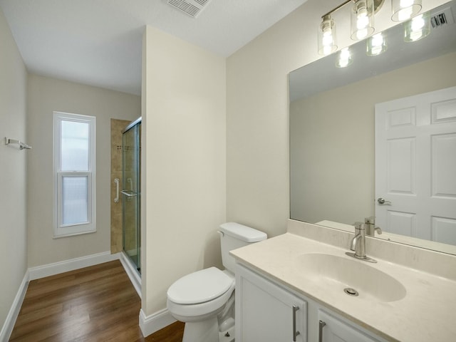 bathroom with vanity, toilet, a shower with door, and hardwood / wood-style floors