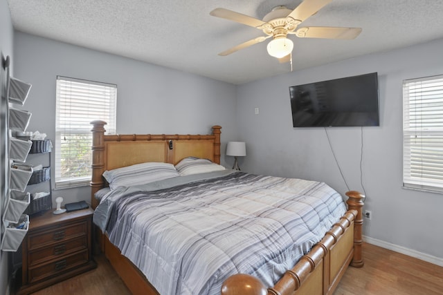 bedroom with ceiling fan, a textured ceiling, baseboards, and wood finished floors