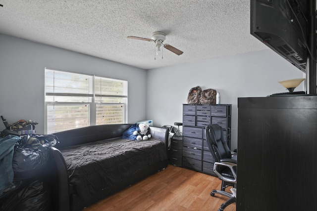 bedroom with a textured ceiling, wood finished floors, and a ceiling fan