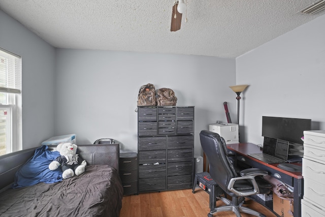 office with visible vents, light wood-style flooring, and a textured ceiling