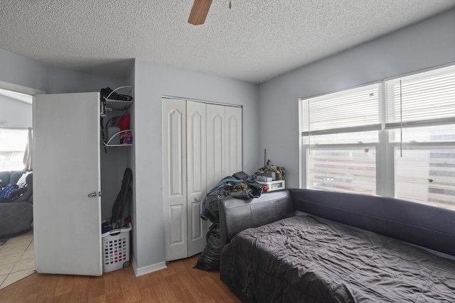 bedroom with a textured ceiling, a closet, a ceiling fan, and wood finished floors