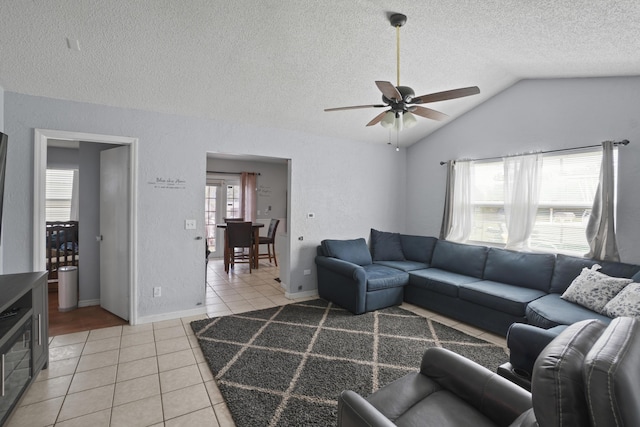 living area with light tile patterned floors, ceiling fan, a textured ceiling, a textured wall, and vaulted ceiling