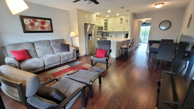 living room featuring dark wood-type flooring and ceiling fan