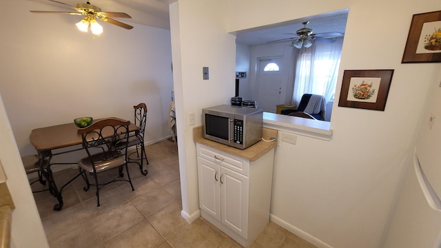 kitchen featuring light tile patterned flooring, white cabinets, and ceiling fan