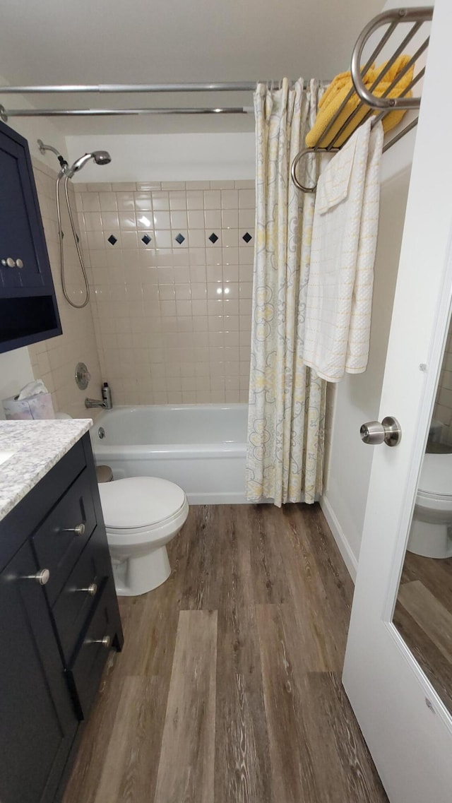 full bathroom featuring vanity, hardwood / wood-style floors, shower / bath combination with curtain, and toilet