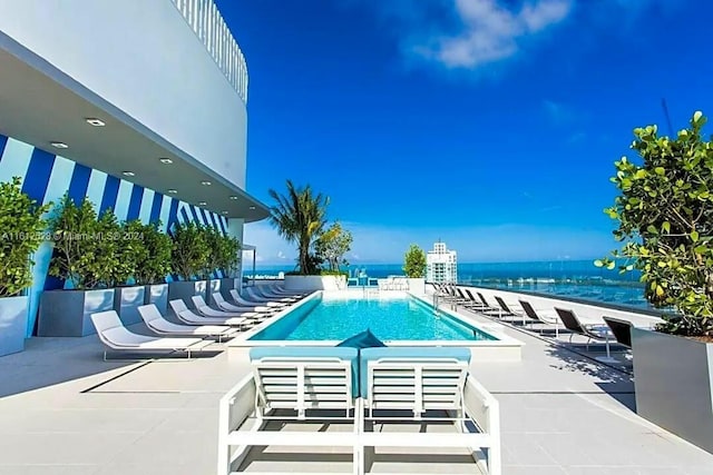 view of swimming pool with a patio and a water view