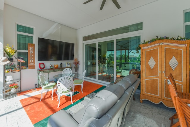 living area featuring a ceiling fan, stone finish floors, and lofted ceiling