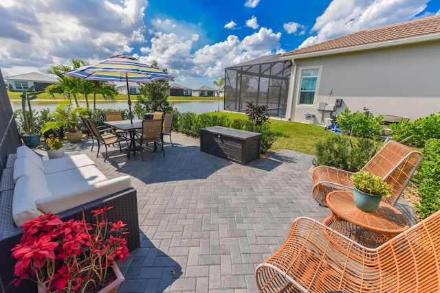 view of patio with a water view, outdoor dining space, and glass enclosure