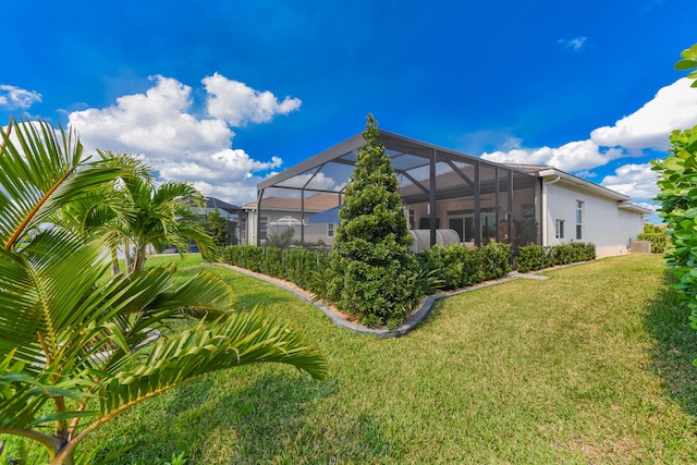 rear view of property with a yard, a lanai, and stucco siding