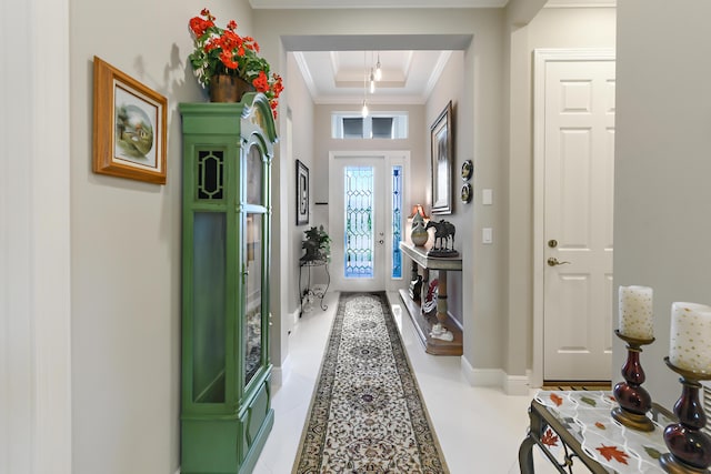 entryway with ornamental molding, baseboards, a raised ceiling, and light tile patterned flooring