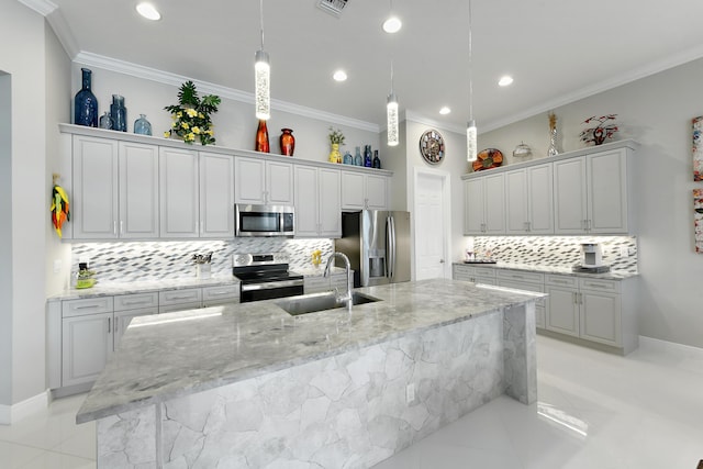 kitchen featuring stainless steel appliances, a sink, tasteful backsplash, crown molding, and a large island with sink