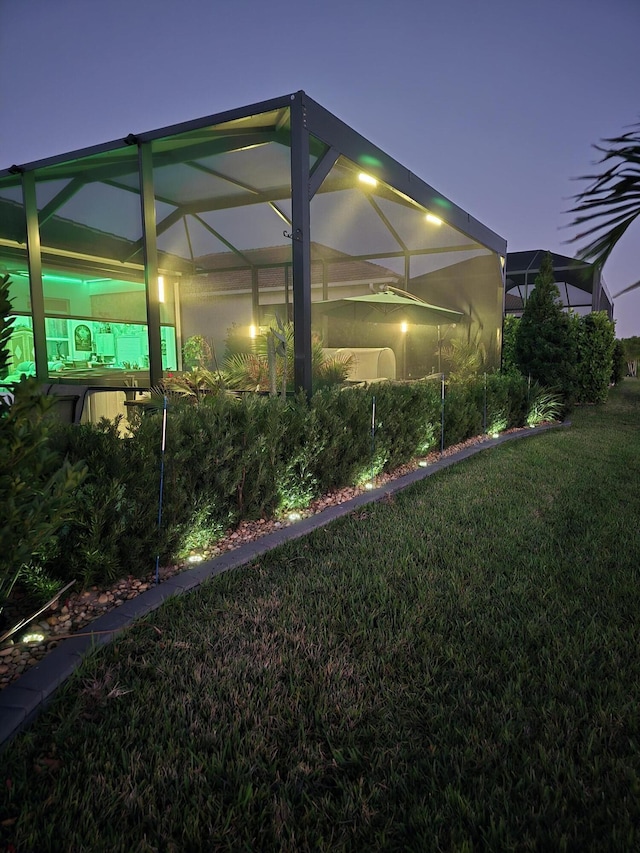 yard at twilight with a lawn and glass enclosure