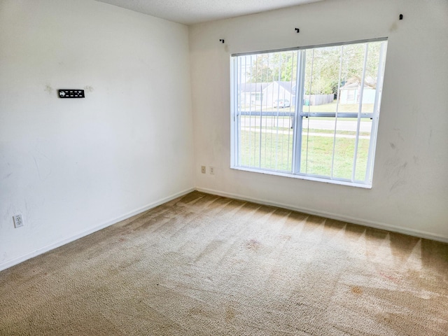 carpeted empty room featuring baseboards