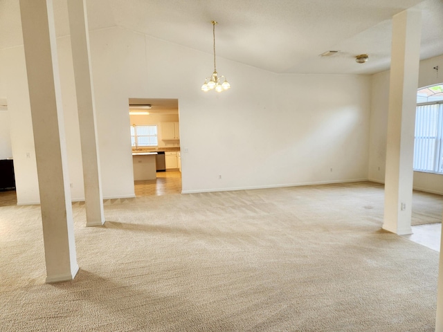 unfurnished living room featuring a chandelier, baseboards, a wealth of natural light, and light colored carpet