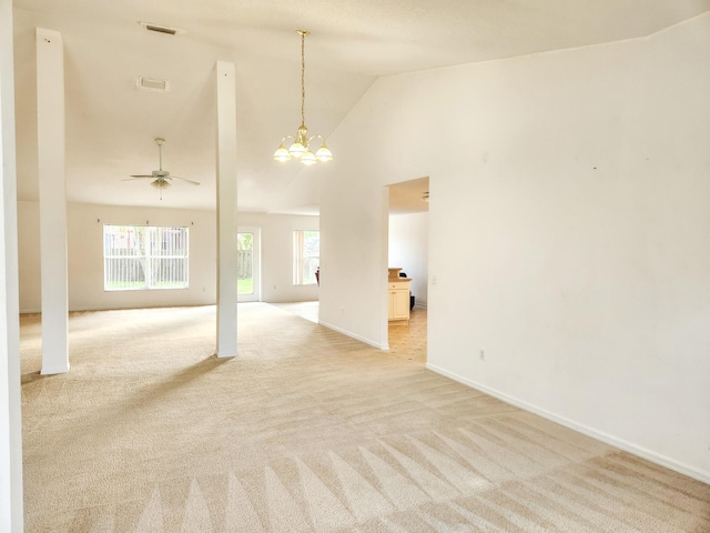 empty room with ceiling fan with notable chandelier, light carpet, baseboards, and visible vents