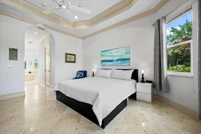 bedroom with crown molding, ceiling fan, ensuite bath, and a tray ceiling