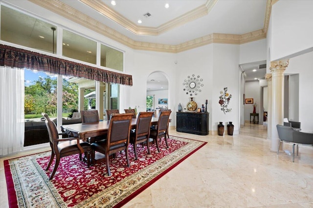 dining room featuring a tray ceiling, crown molding, decorative columns, and a towering ceiling