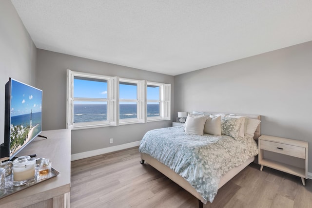 bedroom featuring a water view and light hardwood / wood-style floors