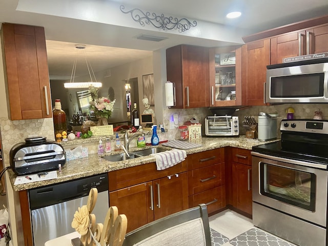 kitchen featuring appliances with stainless steel finishes, decorative backsplash, sink, and light stone countertops